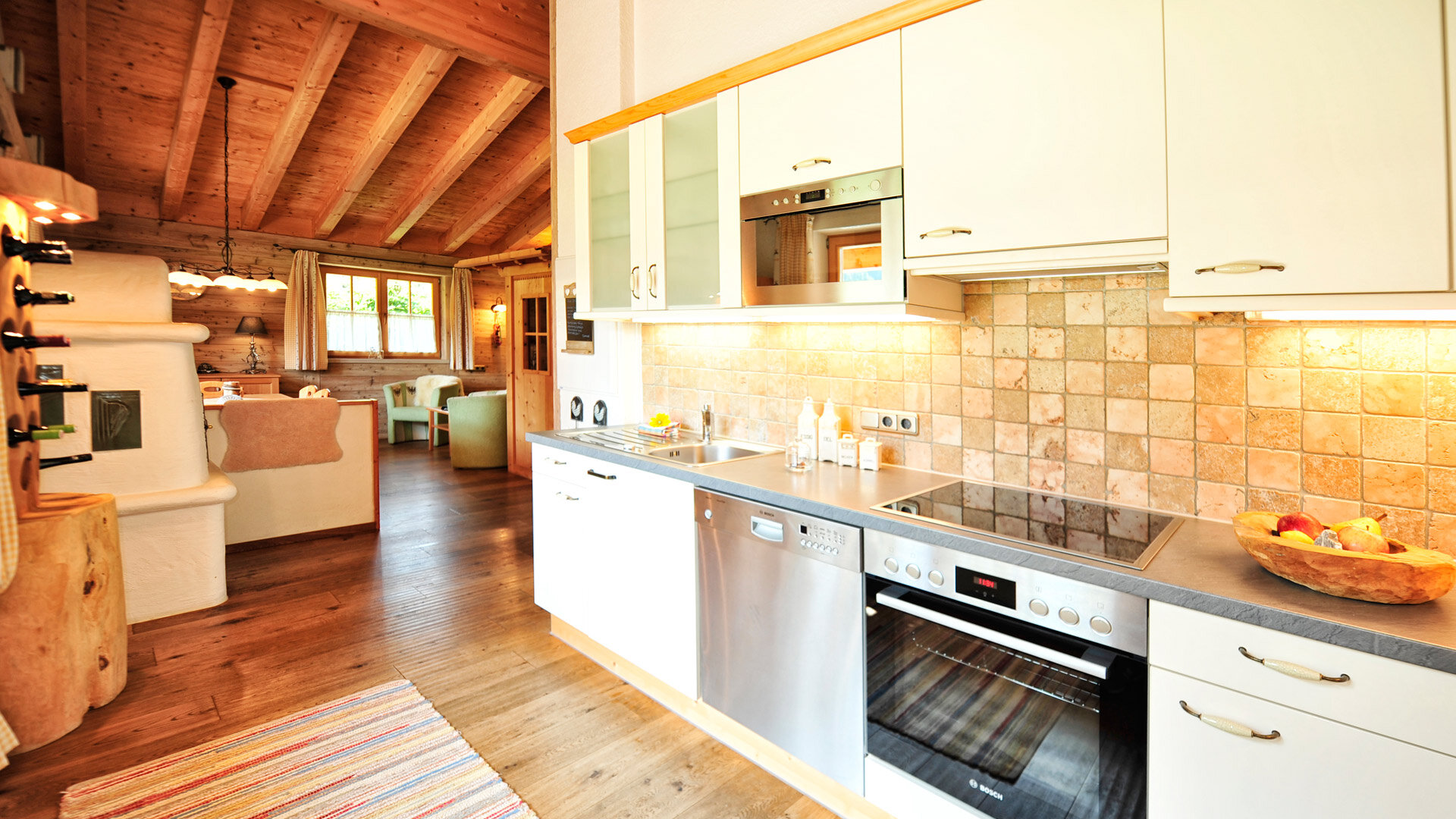 Moderne Küche im Chalet mit Holzdecke, Fliesenwand, Elektrogeräten und gemütlichem Wohnbereich.